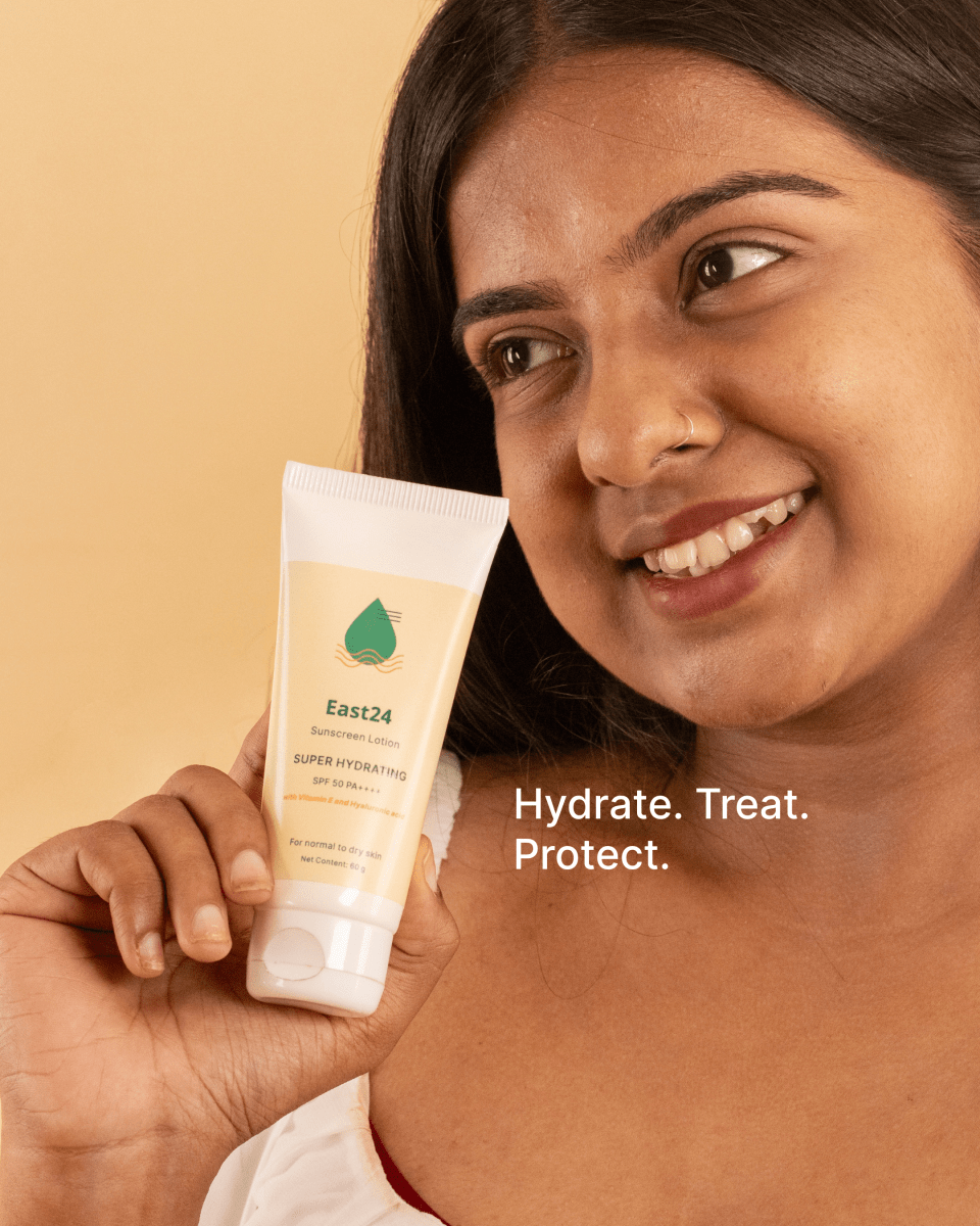 Woman holding a tube of East24 SPF 50 PA++++ moisturizing sunscreen with a beige background